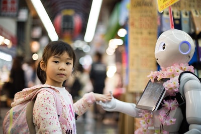 女孩左手躺在白色数码机器人上的照片